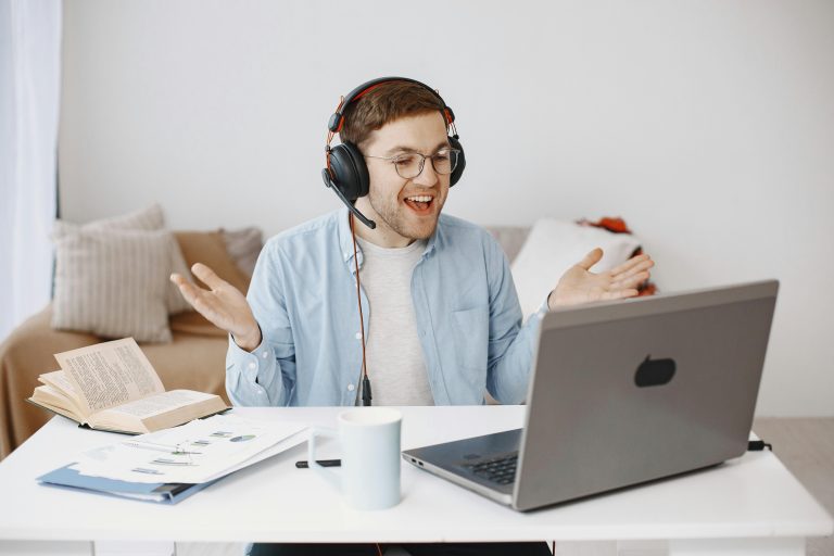 A worker sitting at a desk, in front of a laptop, wearing headphones.