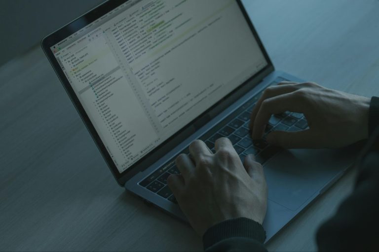 A developer working in the WebStorm IDE, showing a project file structure and TypeScript React components on a MacBook.