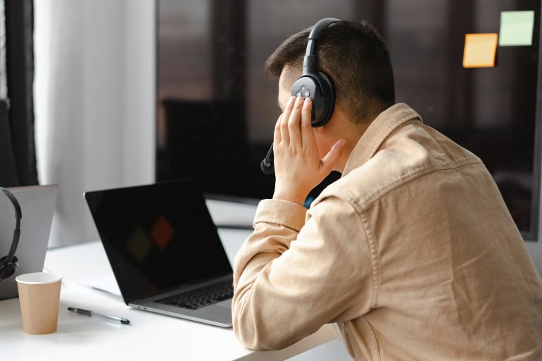 A guy with a headset in front of a laptop.
