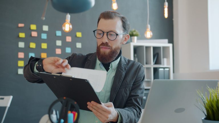 Business professional reviewing a Microsoft 365 security checklist on a clipboard in a modern office setup.